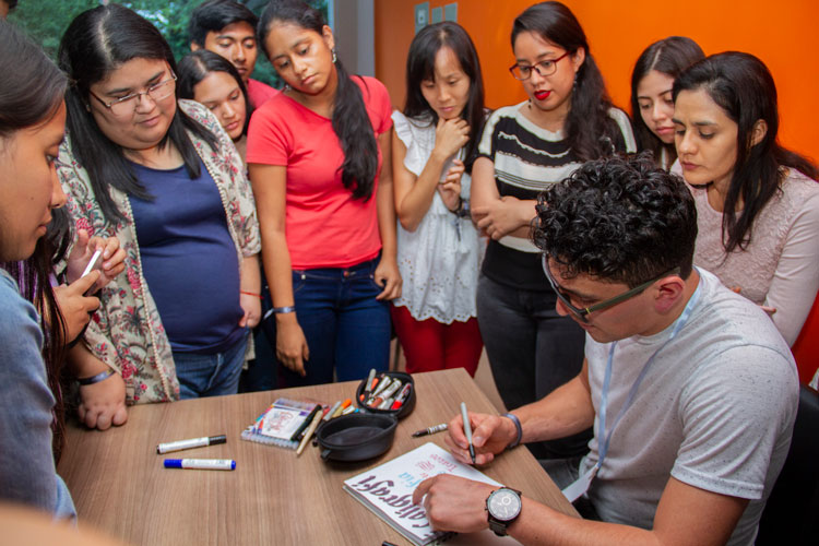 Persona escribbiendo en libreta dando instrucciones a personal de alrededor